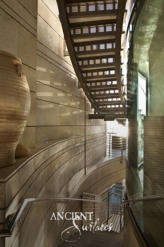 Curved stairwell lined in reclaimed limestone panels with a large antique stone urn