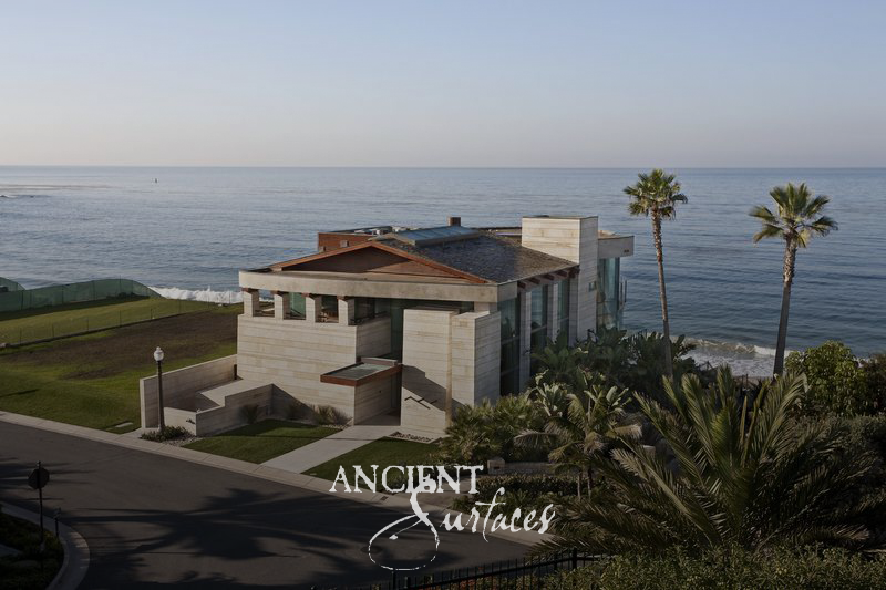 Limestone-clad beach house on the bluff above the Pacific Ocean, framed by palms
