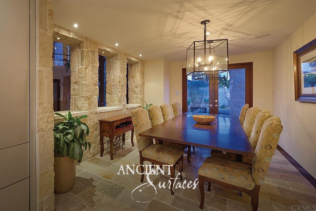 Dining room framed by a reclaimed limestone wall with antique stone flagstone flooring