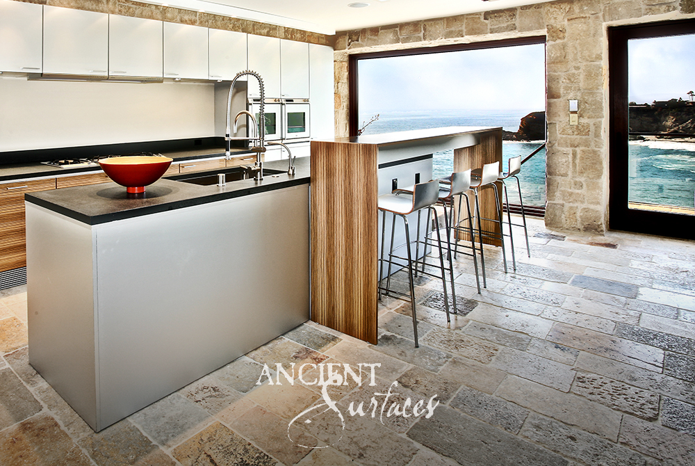 Coastal kitchen with antique reclaimed limestone flooring and rough stone wall cladding opening to the ocean