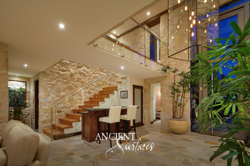 Entry hall at night with reclaimed limestone wall cladding and antique stone flagstone floors