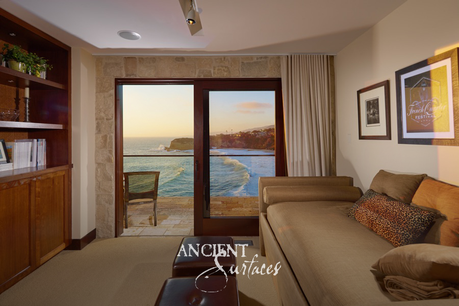 Sitting room with a reclaimed limestone clad wall opening onto an ocean-view stone terrace