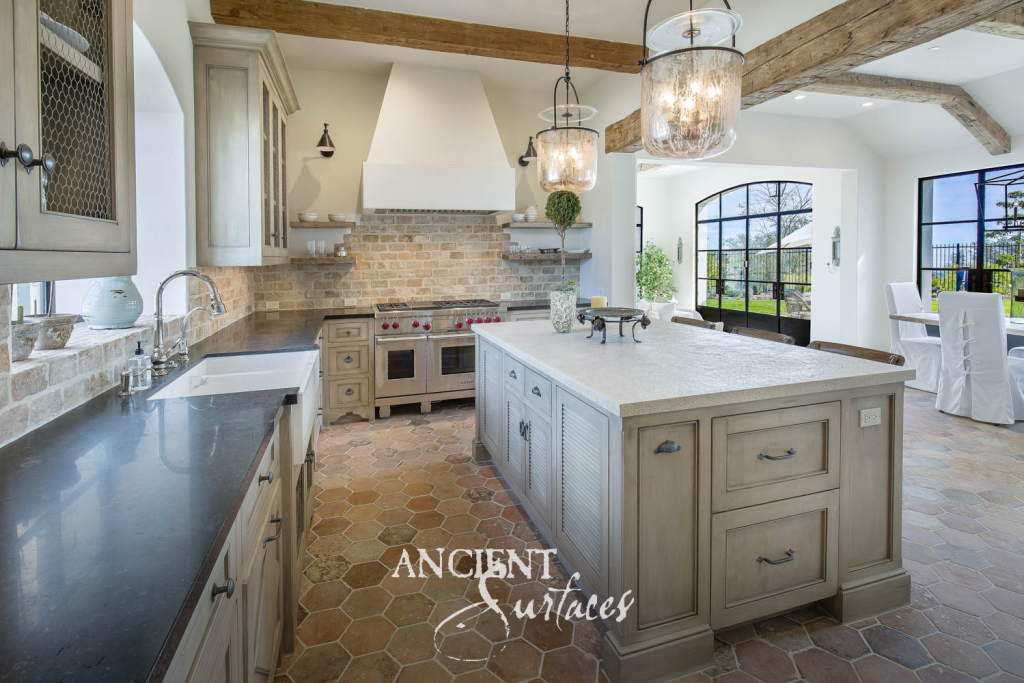 Mediterranean kitchen with antique terracotta hexagon floor tiles, reclaimed timber beams, and a stone backsplash