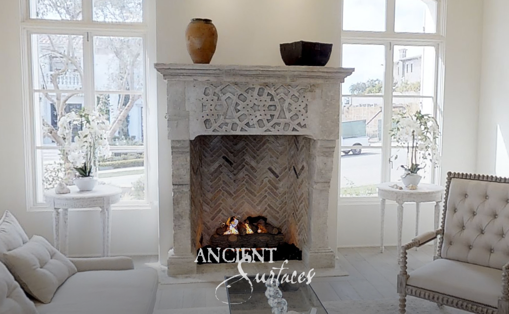 Hand-carved antique limestone fireplace mantel with a herringbone brick firebox