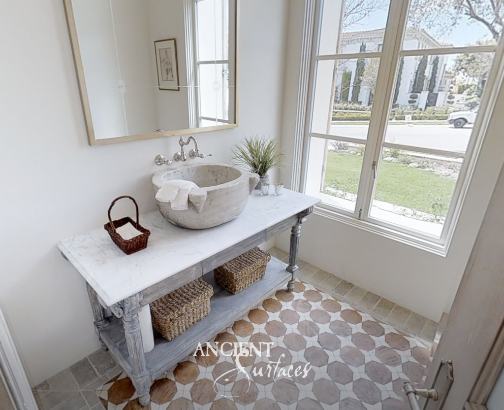 Hand-carved antique stone basin on a marble washstand above a patterned terracotta floor