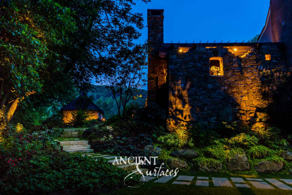 Reclaimed stone garden wall and limestone steps lit at night beside the estate grounds